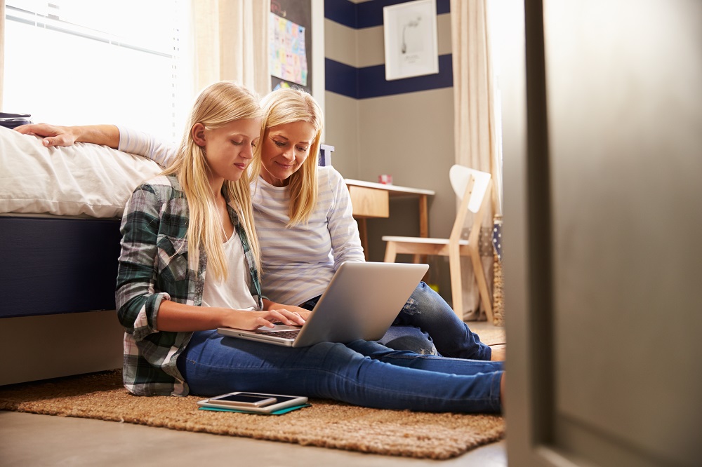 Mother and teenage daughter working on laptop computer.