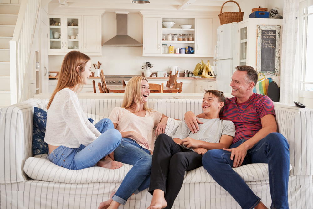 Family of four sitting on couch at home.